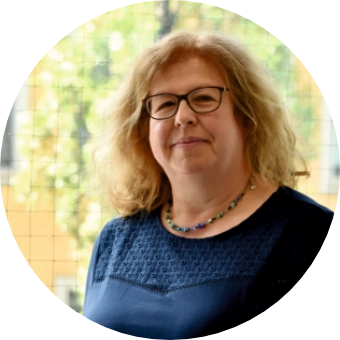 Porträt von Alexandra Mühlhuber, Dozentin bei MaBayern, mit freundlichem Lächeln vor Fenster mit Naturhintergrund